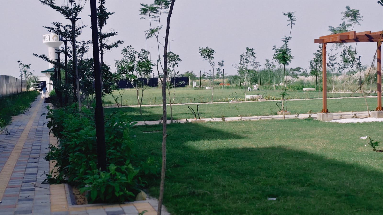 Green lawns and pergola in the park beside MET City Celeste