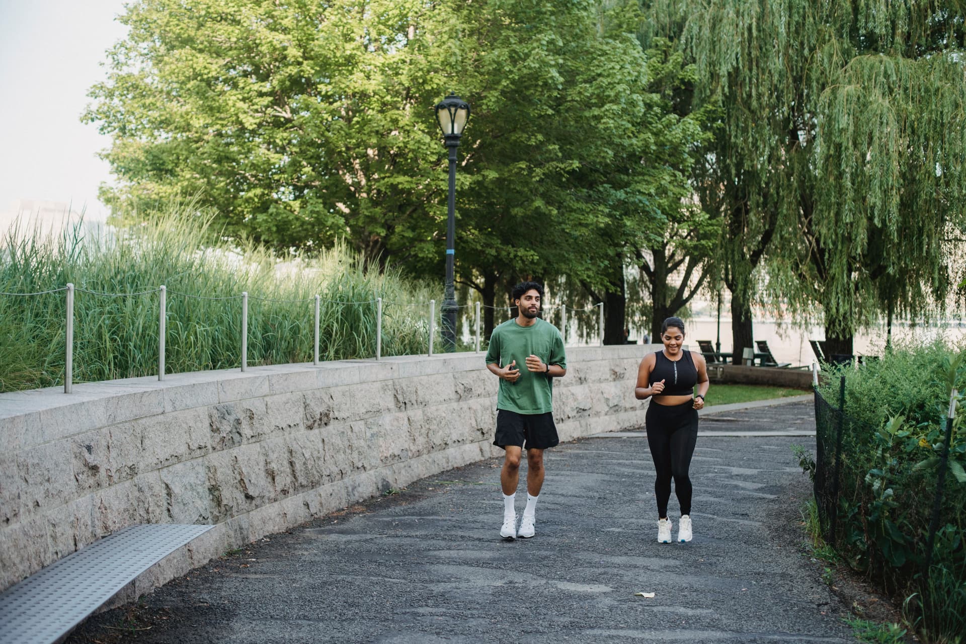 Couple jogging on a tree-lined riverside promenade