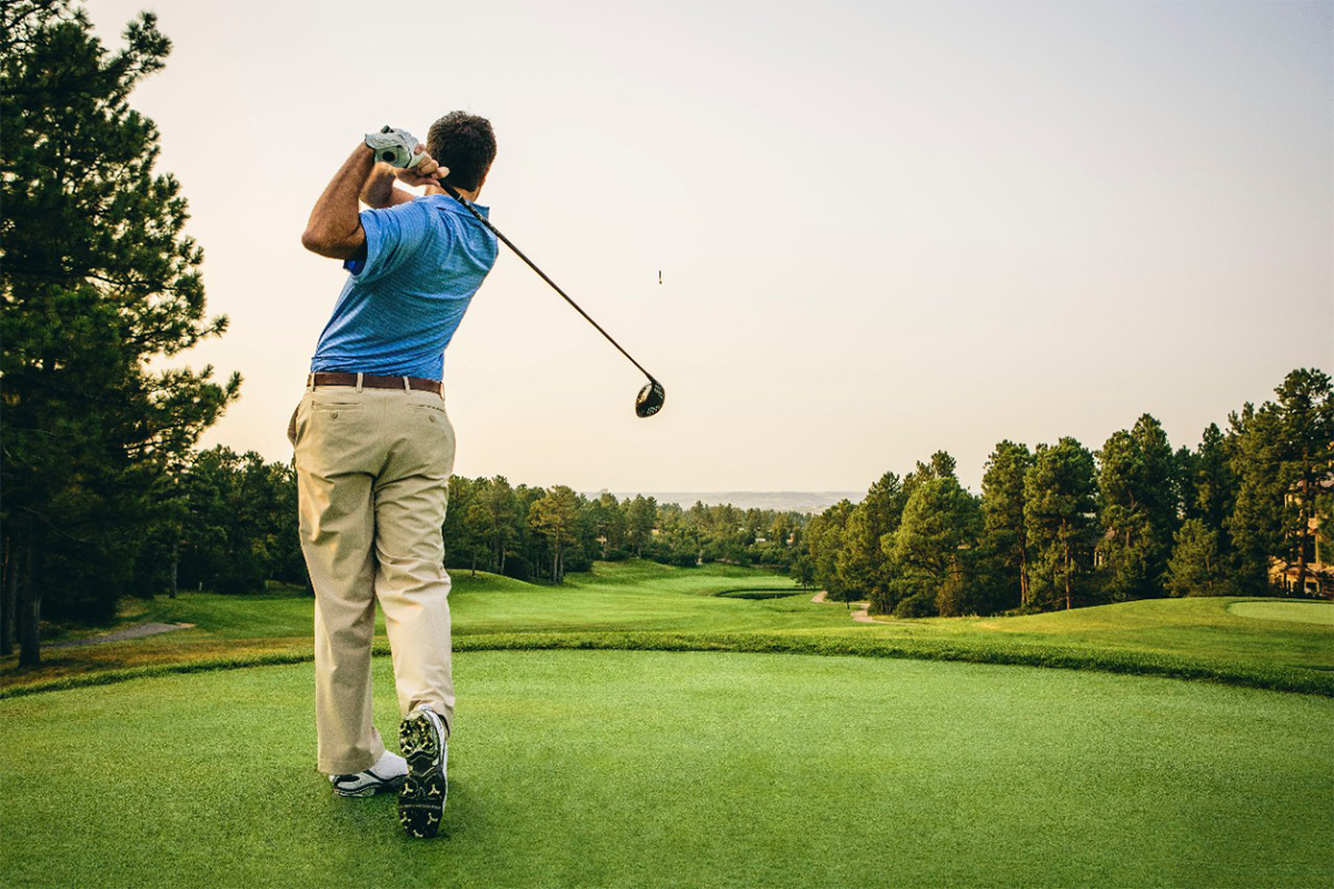 Golfer teeing off on a lush championship golf course